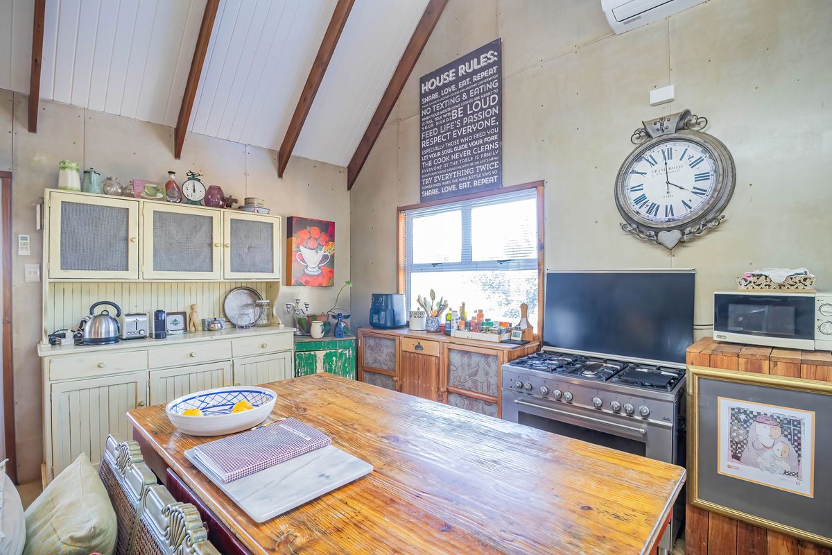 A rustic kitchen featuring a vaulted ceiling with exposed timber beams, built-in cabinetry, and a gas stove, offering a cozy and character-filled cooking space.