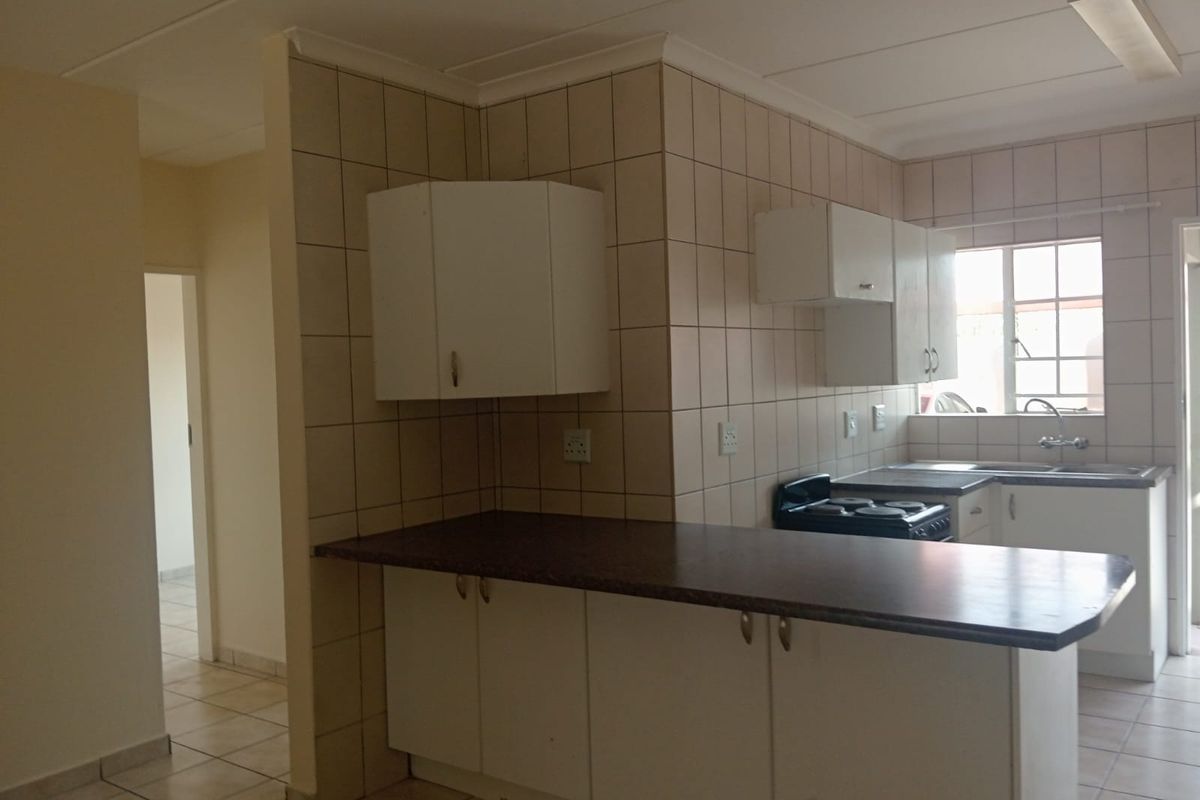 A functional kitchen featuring white cabinetry, laminate countertops, tiled splashbacks, and a freestanding stove, offering a clean and practical layout.