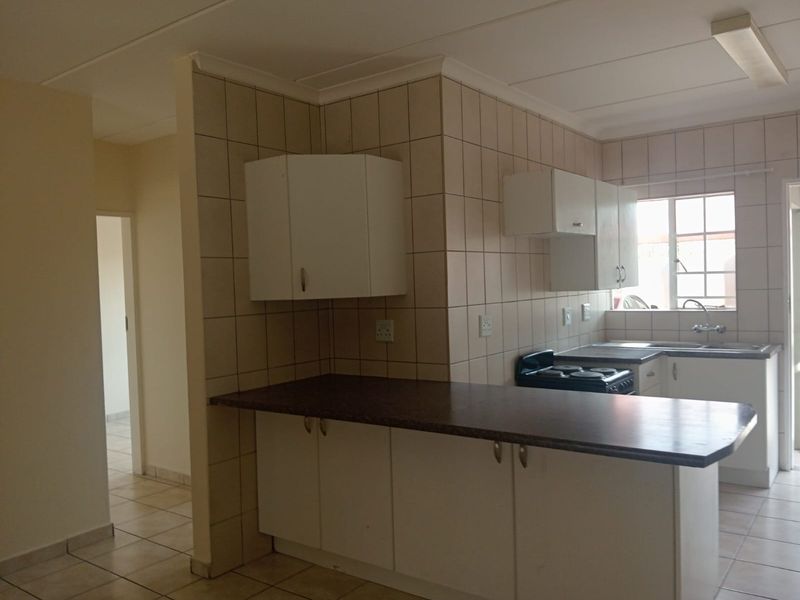A functional kitchen featuring white cabinetry, laminate countertops, tiled splashbacks, and a freestanding stove, offering a clean and practical layout.
