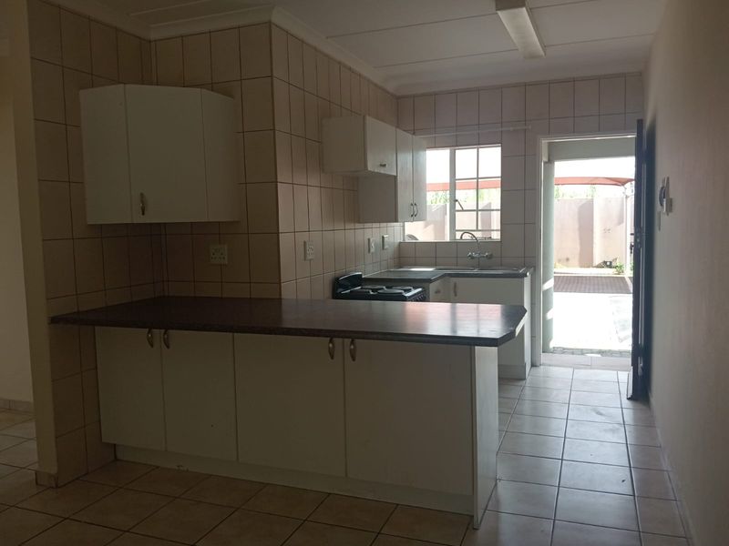 A functional kitchen featuring built-in cabinetry, tiled splashbacks, and a breakfast counter, with direct access to an outdoor area.
