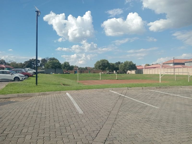 Outdoor communal sports facility featuring a small soccer field with goal posts, adjacent to a paved parking area within the residential complex.