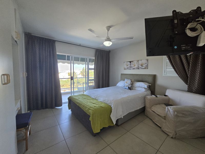 Spacious bedroom featuring tiled flooring, a ceiling fan, and direct access to a private balcony through sliding glass doors.