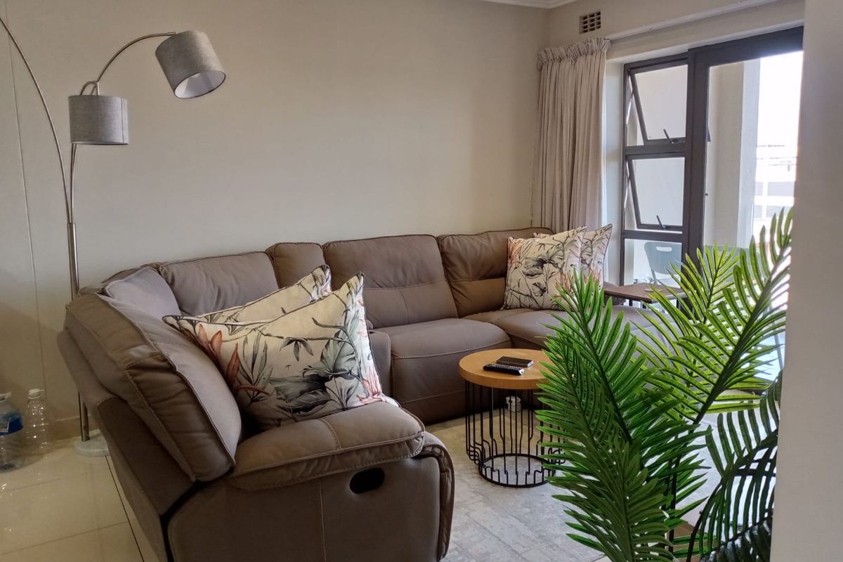 A comfortable living room featuring tiled flooring, recessed lighting, and large aluminium windows that provide natural light.