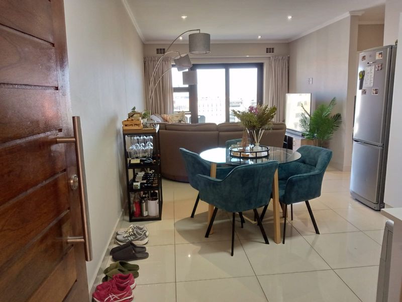 An open-plan living and dining area featuring tiled flooring, recessed lighting, and a sliding glass door leading to an outdoor space.