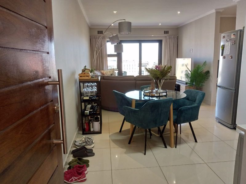 Open-plan living and dining area featuring tiled flooring, recessed lighting, and a large sliding door providing access to the balcony.
