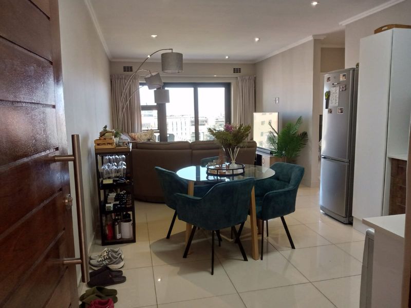 An open-plan living and dining area featuring tiled flooring, recessed lighting, and a large sliding glass door providing natural light and access to the exterior.