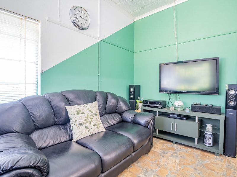 A living room featuring tiled flooring and venetian blinds, currently finished with a two-tone painted wall design.