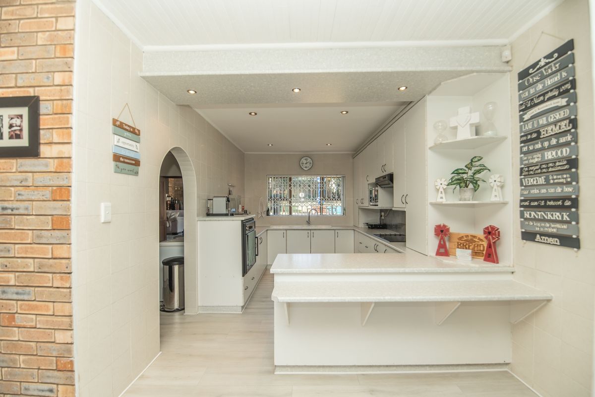 A functional kitchen featuring white cabinetry, laminate countertops, a breakfast bar, built-in oven, and a classic arched doorway leading to an adjacent space.