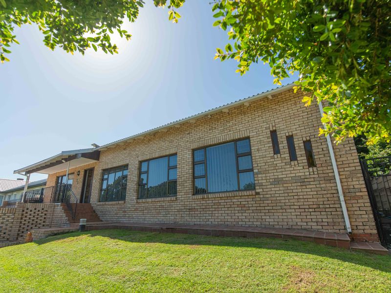 A well-maintained single-story house featuring a classic face brick facade, large aluminium-framed windows, and a welcoming tiled entrance with wrought iron railings.