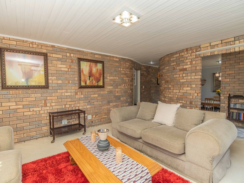 A living room featuring exposed brick walls and a white tongue and groove ceiling, providing a rustic aesthetic with potential for modern updates.