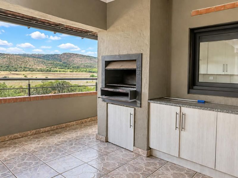 Covered patio featuring a built-in braai, granite-topped cabinetry, and expansive views of the surrounding landscape.