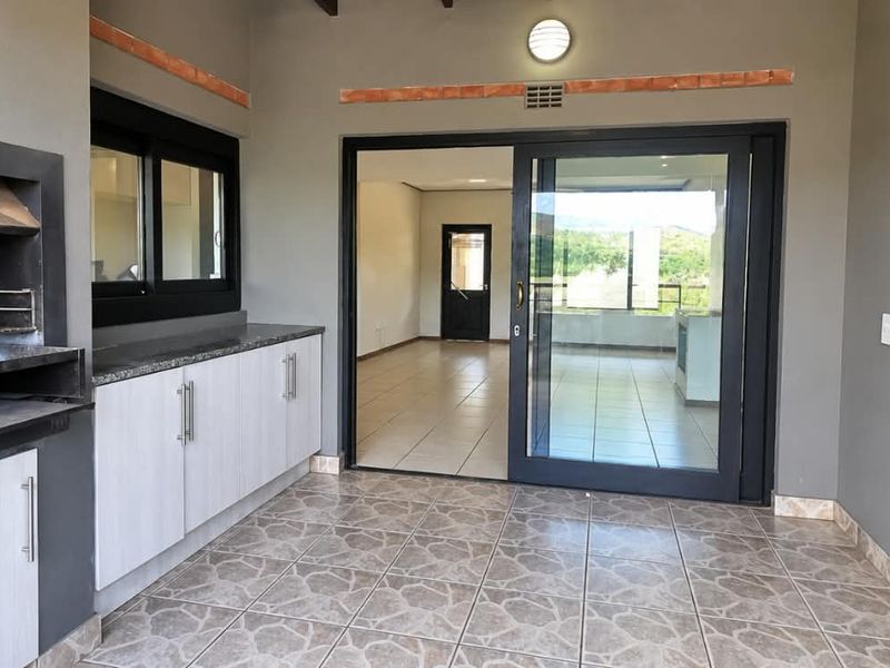 Covered patio featuring a built-in braai, granite-topped cabinetry, and sliding glass doors providing access to the interior living space.