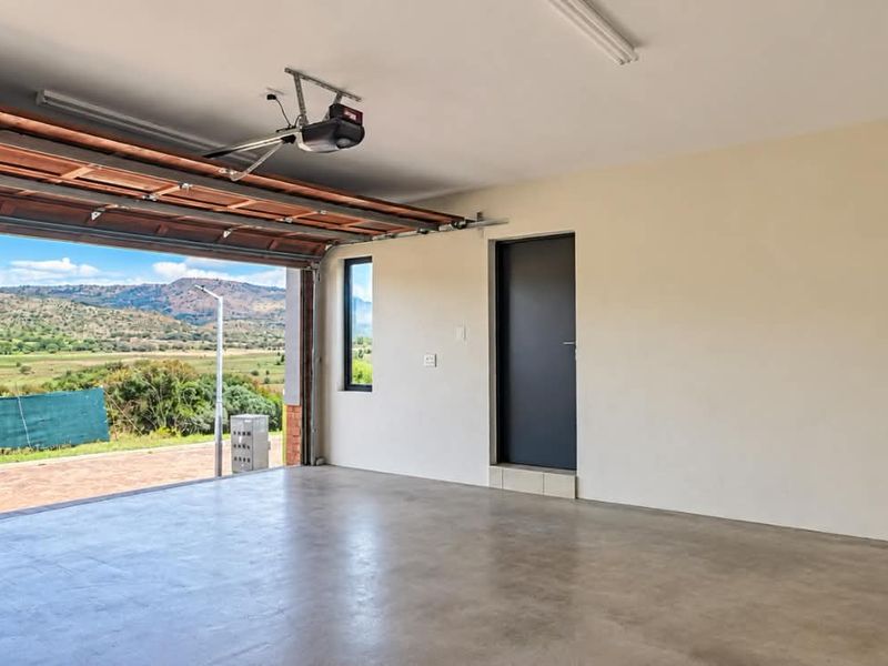 Spacious, well-maintained garage featuring smooth concrete flooring, an automated door system, and direct internal access, offering scenic views of the surrounding landscape.