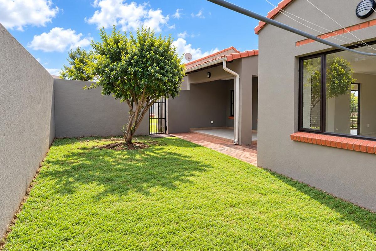 A well-maintained rear garden featuring a brick-paved patio, neat lawn, and secure boundary walls, providing a private outdoor space.