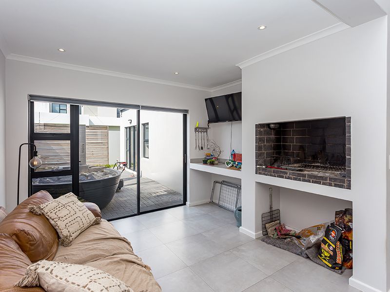 Covered patio area featuring a built-in braai, tiled flooring, and sliding glass doors providing seamless access to the outdoor space.