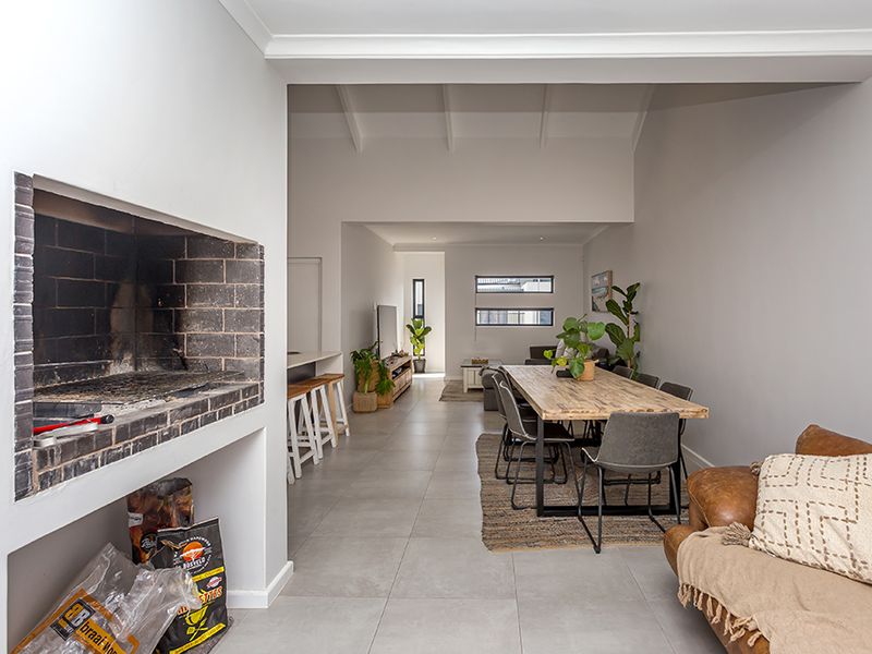 Spacious open-plan living and dining area featuring a built-in indoor braai, vaulted ceilings, and modern tiled flooring throughout.