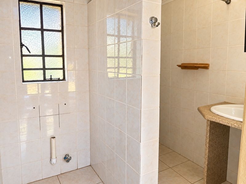 A partially finished bathroom featuring tiled surfaces, a built-in vanity with basin, and exposed plumbing connections ready for final fixture installation.