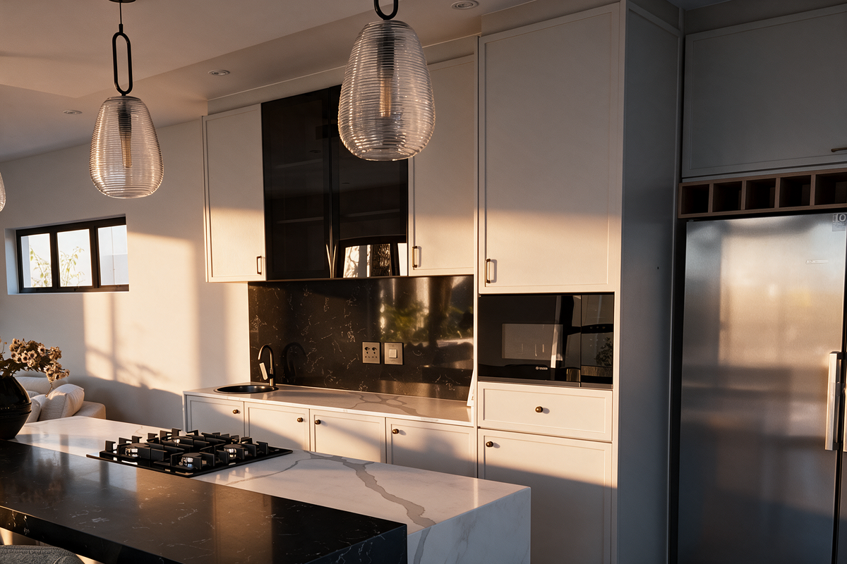 Modern kitchen featuring a large island with gas hob, stone countertops, black marble backsplash, integrated appliances, and stylish pendant lighting in a warm setting.