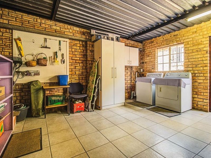 A functional laundry area featuring exposed brick walls, tiled flooring, and practical utility connections, providing a versatile space for household tasks.