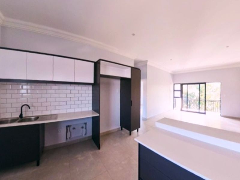 Modern open-plan kitchen and living area featuring sleek cabinetry, subway tile backsplash, and sliding doors leading to a balcony.