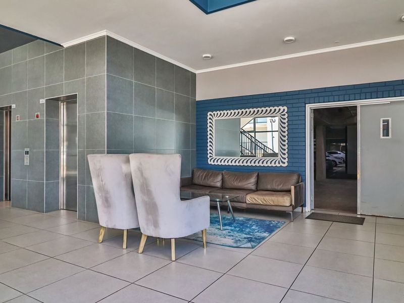 Modern apartment building lobby featuring tiled flooring, elevator access, and a decorative blue brick feature wall.