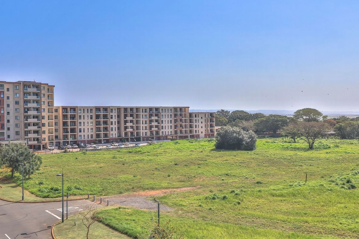 An elevated aerial view of the apartment complex, surrounding paved roads, and adjacent open green space.
