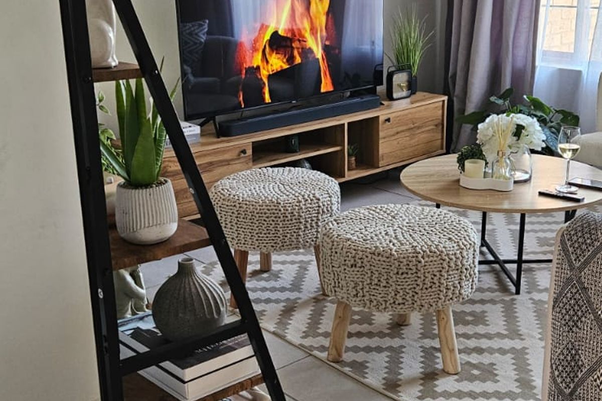 A cozy living room featuring neutral tiled flooring and natural light from the window, creating a comfortable and inviting atmosphere.