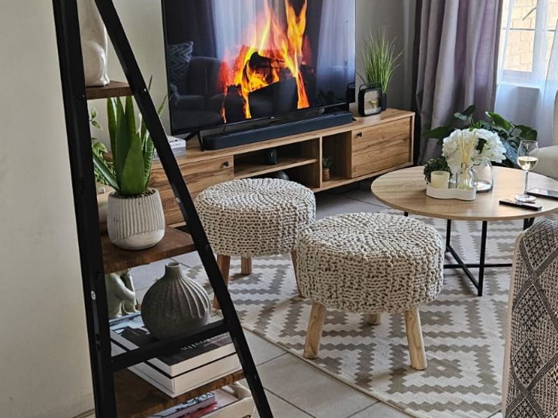 A cozy living room featuring neutral tiled flooring and natural light from the window, creating a comfortable and inviting atmosphere.
