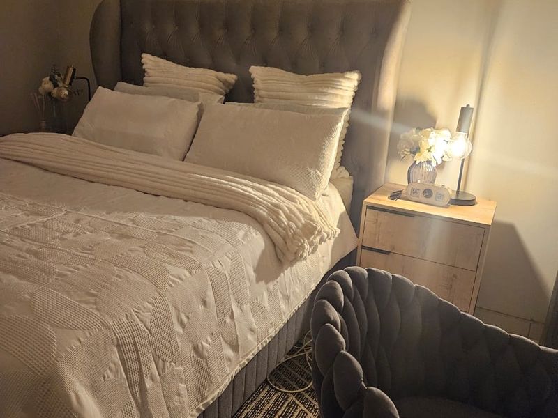 A cozy bedroom featuring a tufted headboard and warm ambient lighting, creating a comfortable and inviting sleeping space.
