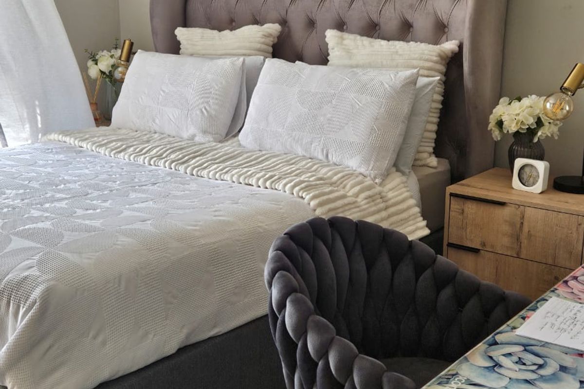 A well-maintained bedroom featuring a tufted upholstered headboard and neutral interior finishes.