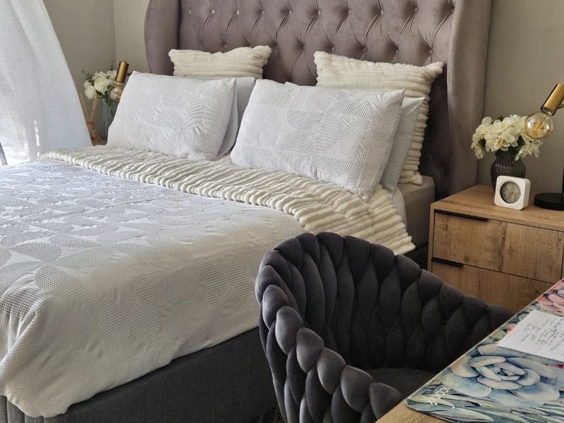 A well-maintained bedroom featuring a tufted upholstered headboard and neutral interior finishes.