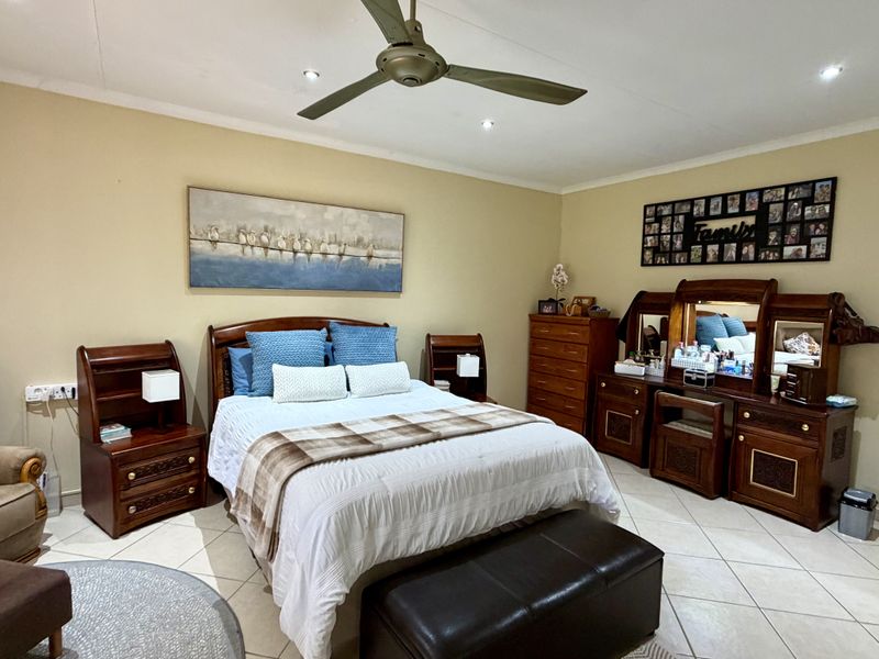 A spacious bedroom featuring tiled flooring, recessed ceiling lighting, and a central ceiling fan, providing a comfortable and functional living space.