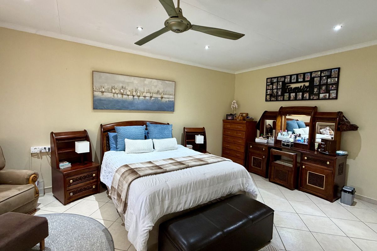 A spacious bedroom featuring tiled flooring, recessed ceiling lighting, and a central ceiling fan, providing a comfortable and functional living space.