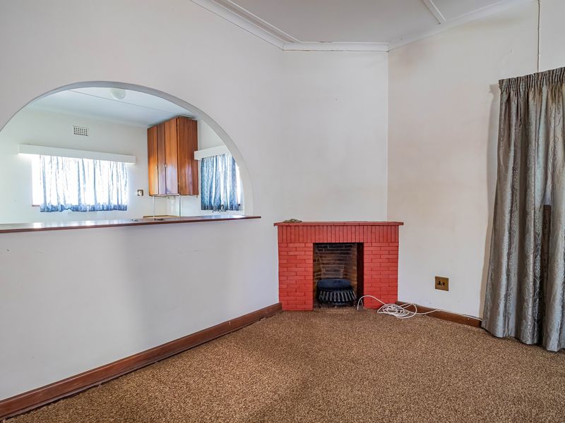 A living room featuring a brick fireplace and a large arched opening looking through to the kitchen area.