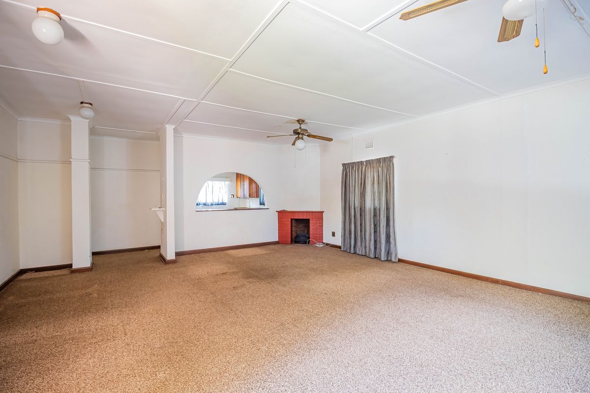 Spacious living area featuring a brick fireplace, ceiling fans, and an arched opening leading to the kitchen area.