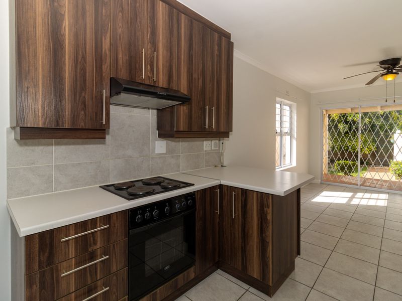 Modern kitchen featuring dark wood cabinetry, built-in oven and hob, tiled flooring, and direct access to the outdoor patio area.