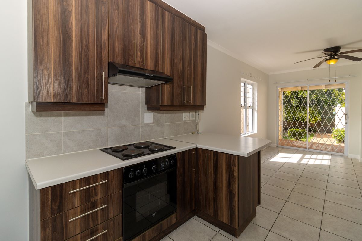 Modern kitchen featuring dark wood cabinetry, built-in oven and hob, tiled flooring, and direct access to the outdoor patio area.