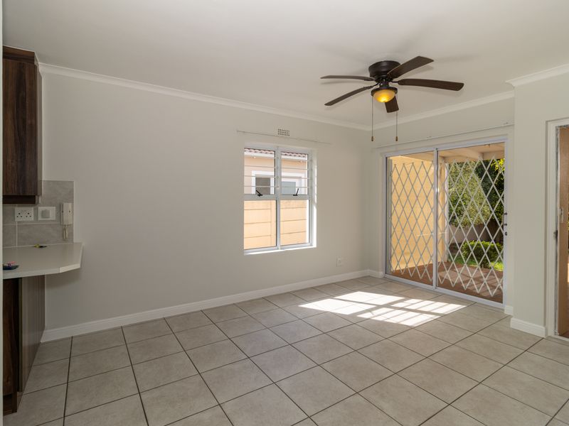 Bright open-plan living area featuring tiled floors, a ceiling fan, and sliding glass doors providing direct access to the outdoor patio.