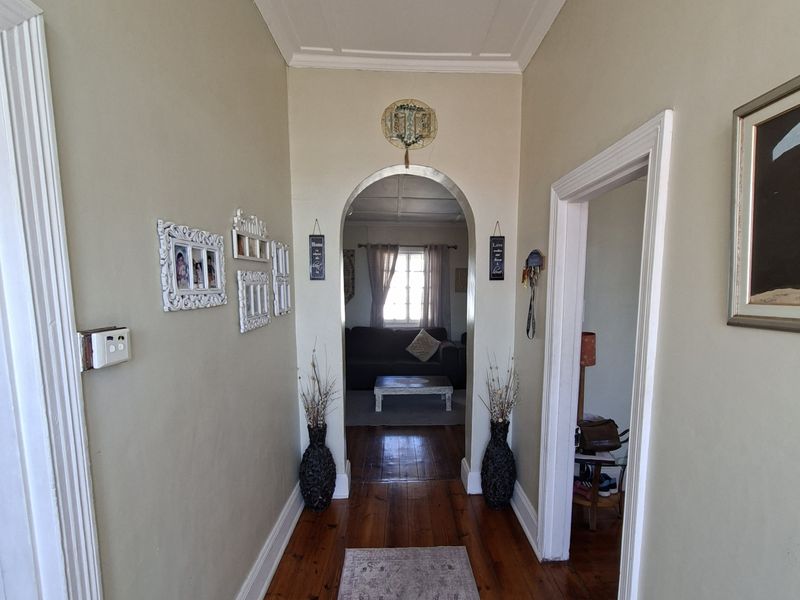 A well-maintained hallway featuring polished timber flooring, a decorative coffered ceiling, and a classic arched doorway leading into the living area.