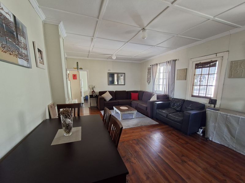 Spacious open-plan living and dining area featuring original timber flooring and a classic coffered ceiling, offering a warm and traditional atmosphere.
