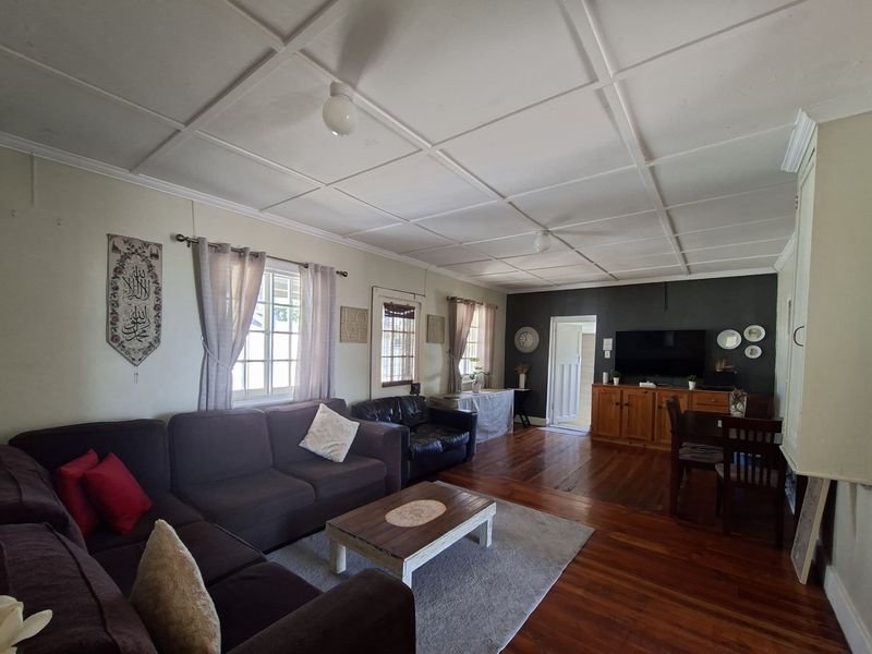 Spacious open-plan living and dining area featuring traditional hardwood flooring and a distinctive coffered ceiling, offering a versatile layout for family living.