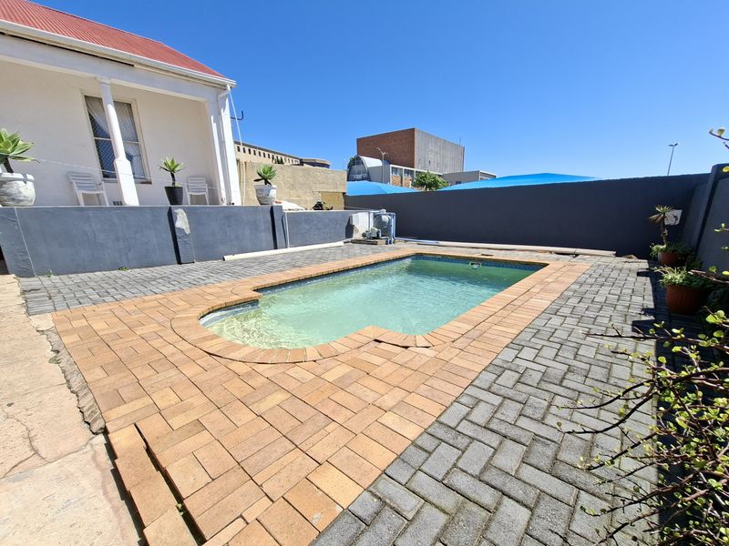 Outdoor pool area featuring a swimming pool surrounded by brick paving and a painted retaining wall.