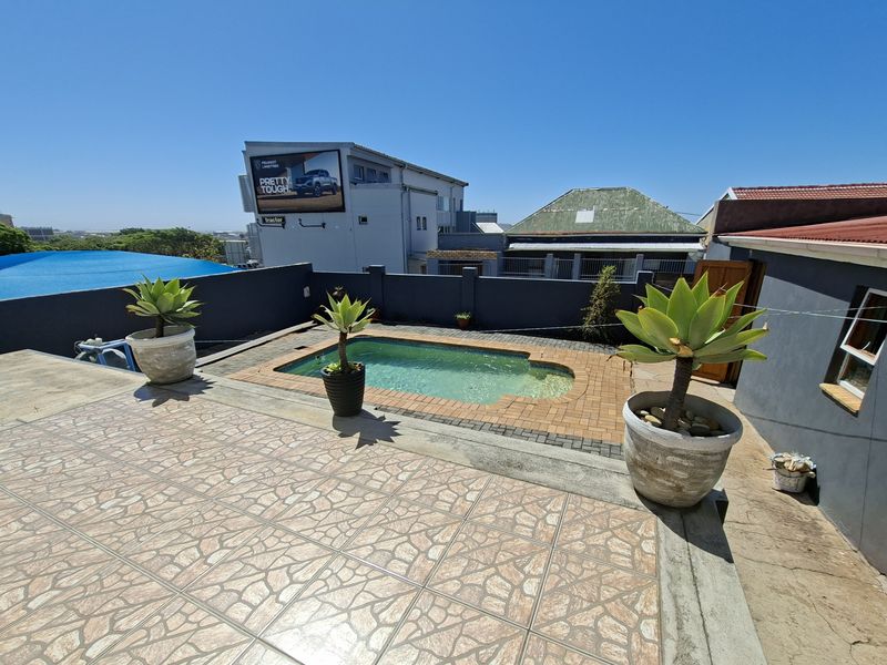 Outdoor pool area featuring a swimming pool, brick paving, and a tiled patio space enclosed by a perimeter wall.