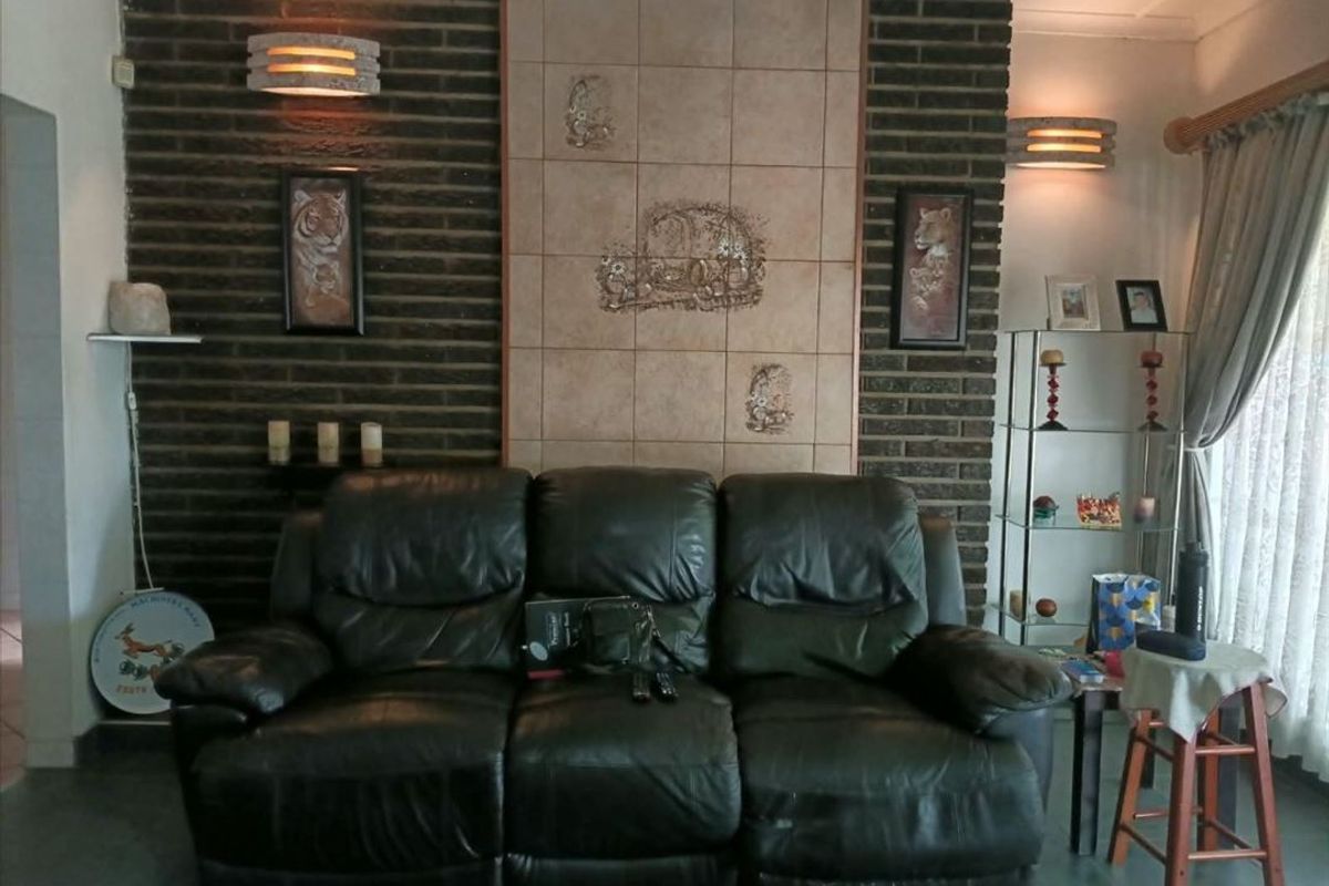 A living room featuring an exposed brick wall with decorative central tiling and wall-mounted lighting fixtures.