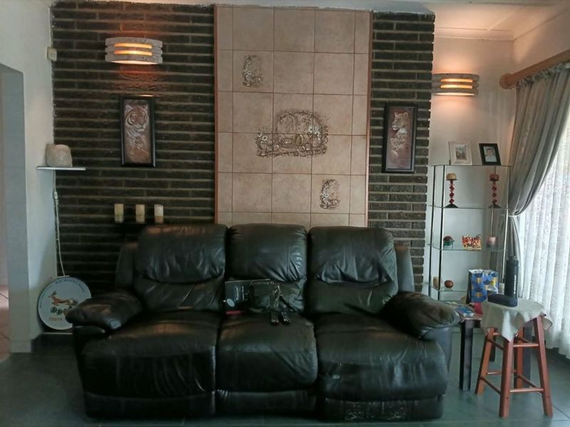 A living room featuring an exposed brick wall with decorative central tiling and wall-mounted lighting fixtures.