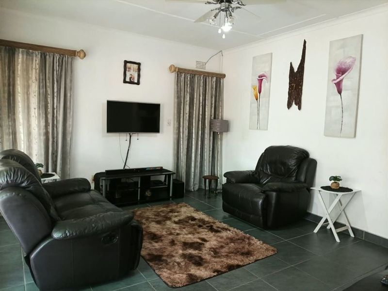 A comfortable living room featuring dark tiled flooring, a ceiling fan, and neutral walls, providing a functional space for relaxation.
