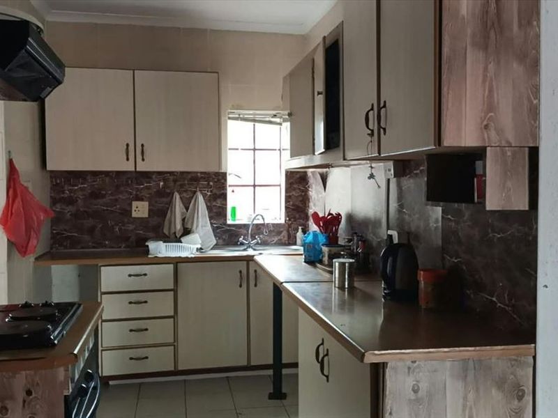 A functional kitchen featuring built-in cabinetry, laminate countertops, a stainless steel sink, and a built-in hob with an extractor fan.