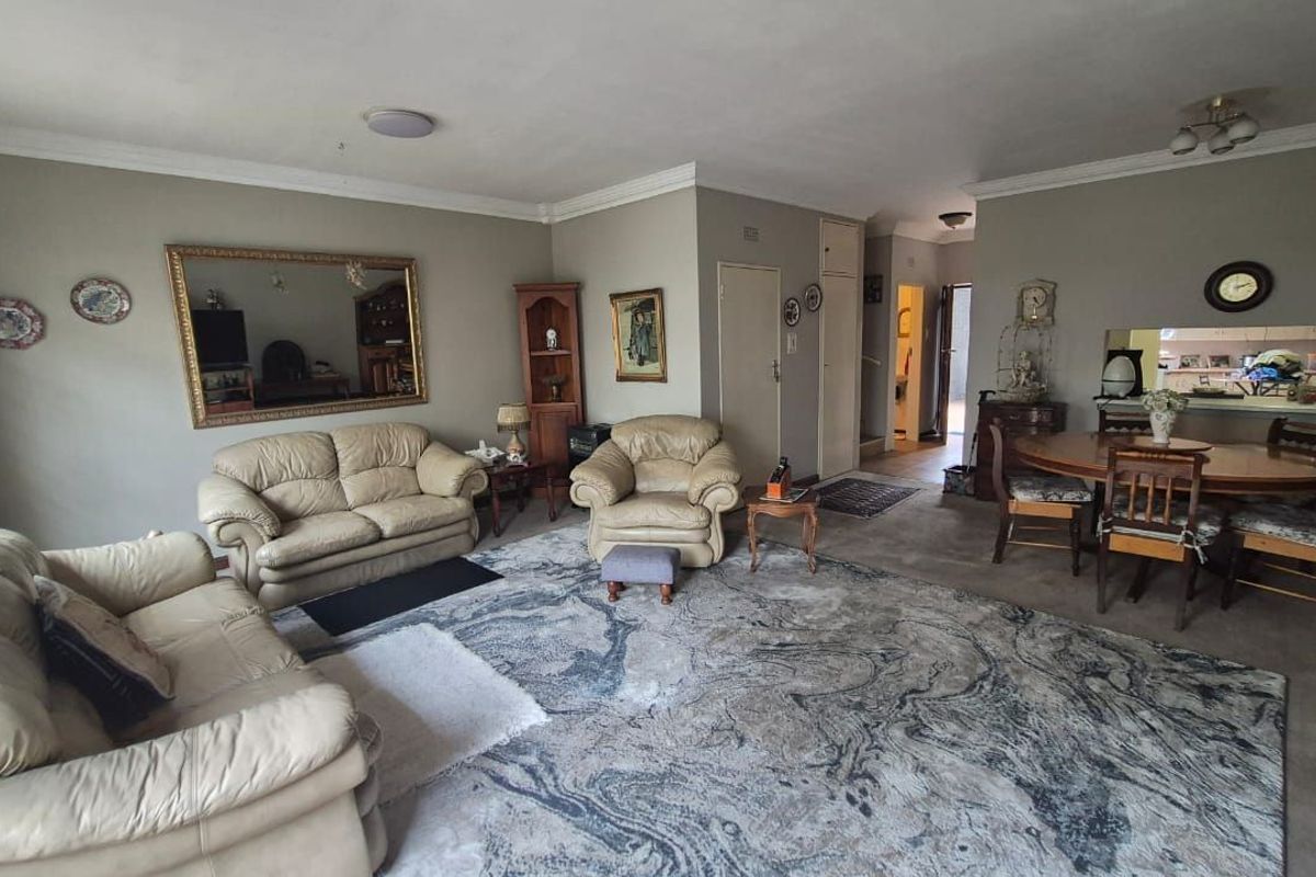 Spacious open-plan living and dining area featuring neutral wall tones, coving, and a convenient pass-through window connecting to the kitchen space.