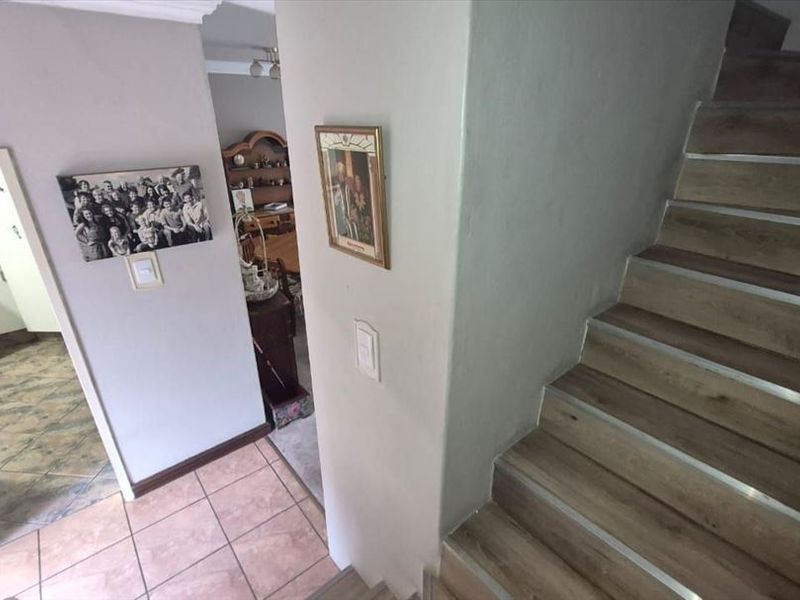 A view of the interior hallway featuring a staircase with laminate treads and tiled flooring, providing access to the kitchen and living areas.