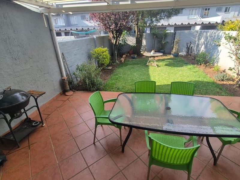 A covered patio area with tiled flooring, leading out to a private garden space with a boundary wall.